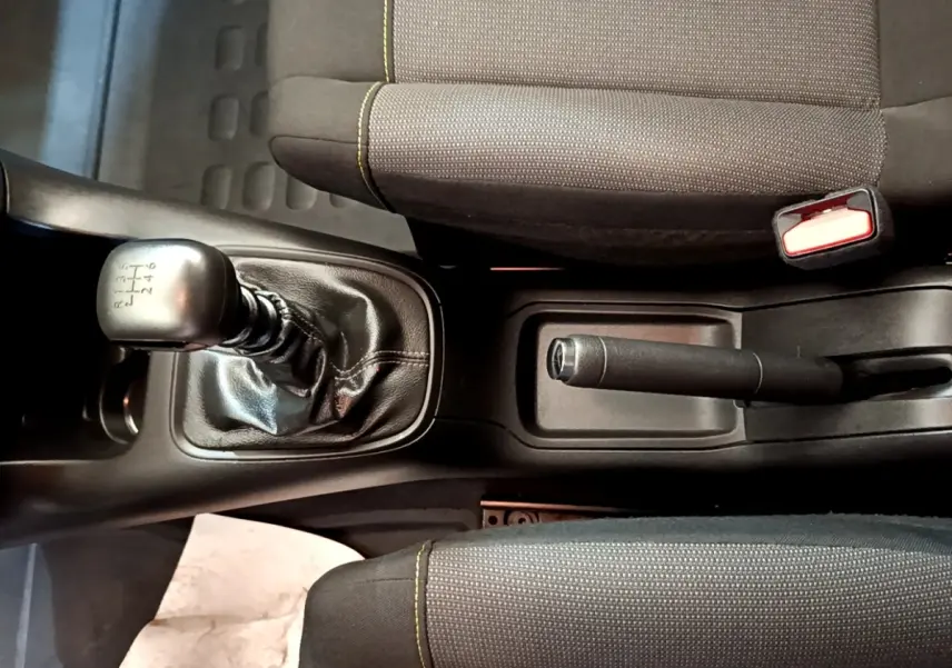 Vue plongeante sur la console centrale d'une Citroën C3 blanche, montrant levier de vitesse manuel et frein à main.