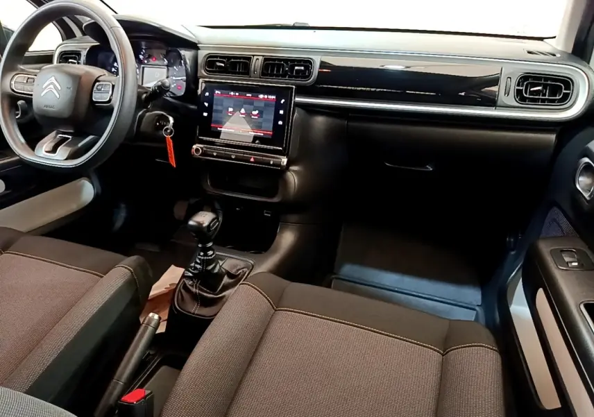 Vue intérieure avant de la Citroën C3 2021 avec tableau de bord noir, écran tactile central et volant multifonctions.