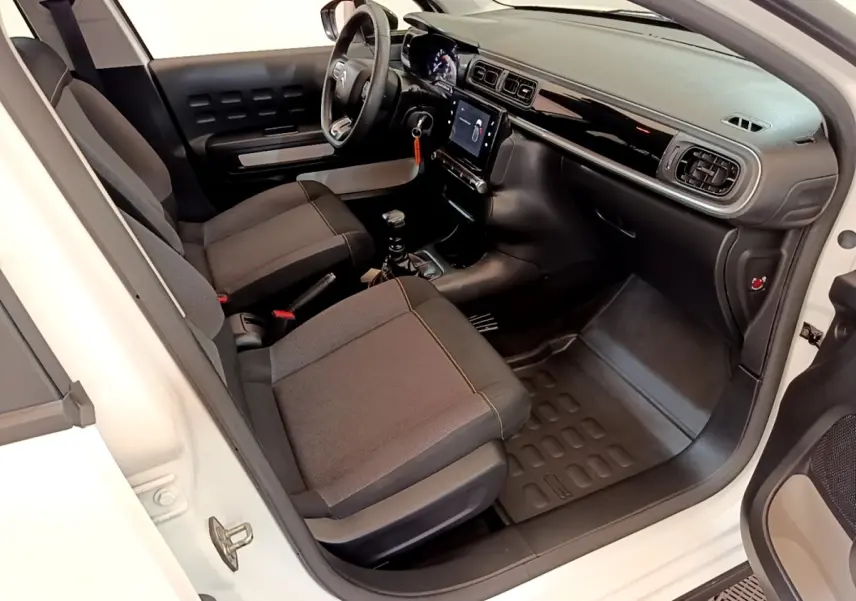 Vue intérieure côté conducteur d'une Citroën C3 blanche 2021, montrant sièges noirs et tableau de bord avec écran tactile.