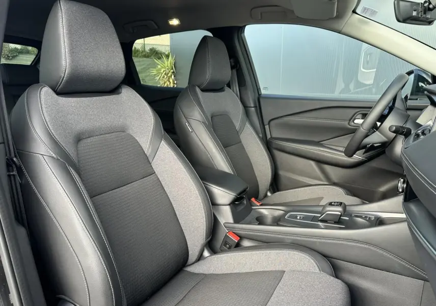Vue intérieure côté droit du Nissan Qashqai 2025, sièges avant bi-matière gris et noir avec console centrale.