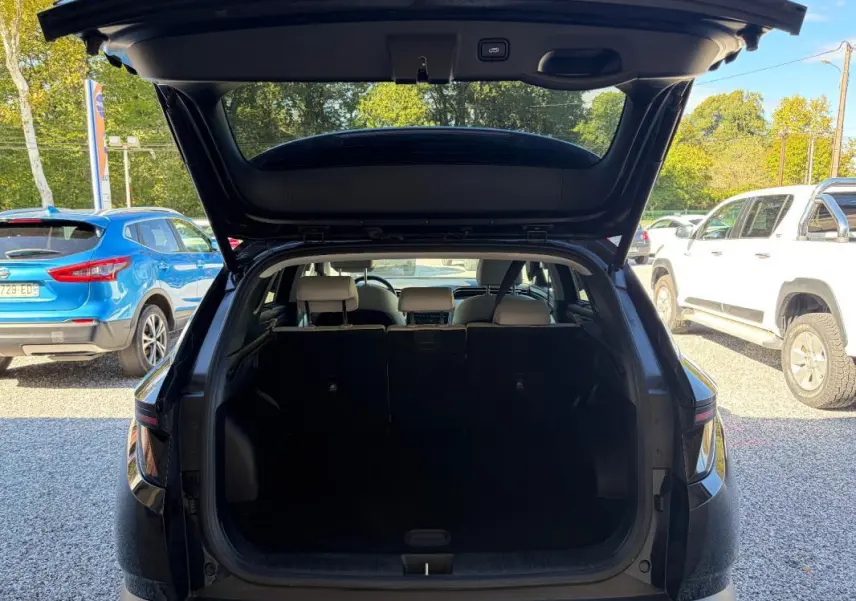 Coffre ouvert vu de l'arrière d'un Hyundai Tucson noir 2022, montrant l'espace de chargement et les sièges arrière.