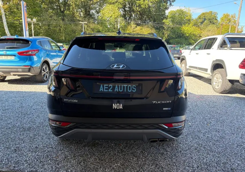 Vue arrière d'un Hyundai Tucson noir 2022 avec feux LED et double sortie d'échappement, stationné sur un sol gravillonné.