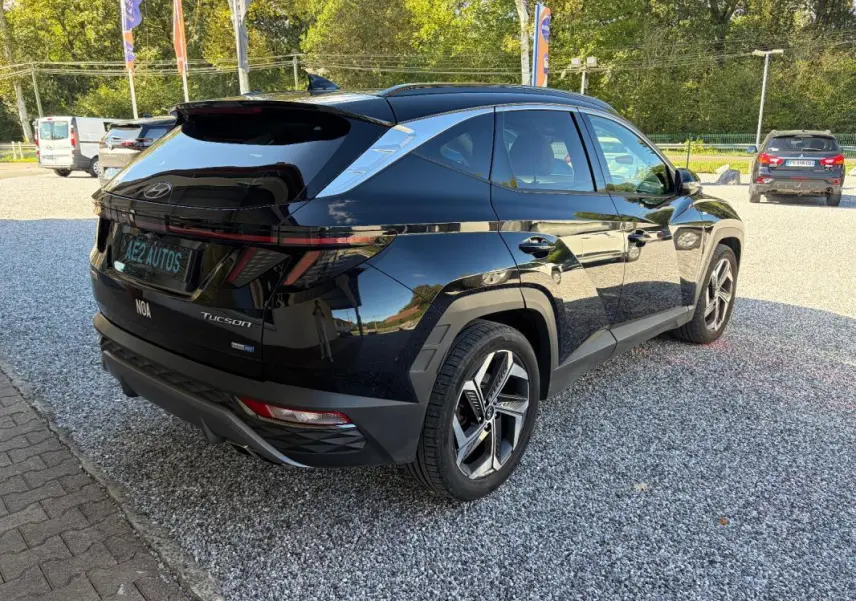 Vue 3/4 arrière droite d’un Hyundai Tucson noir 2022 avec barres de toit et jantes alliage modernes.