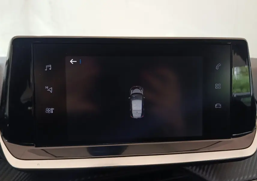 Écran tactile central affichant une vue aérienne du véhicule Peugeot 208 blanc dans l'habitacle.