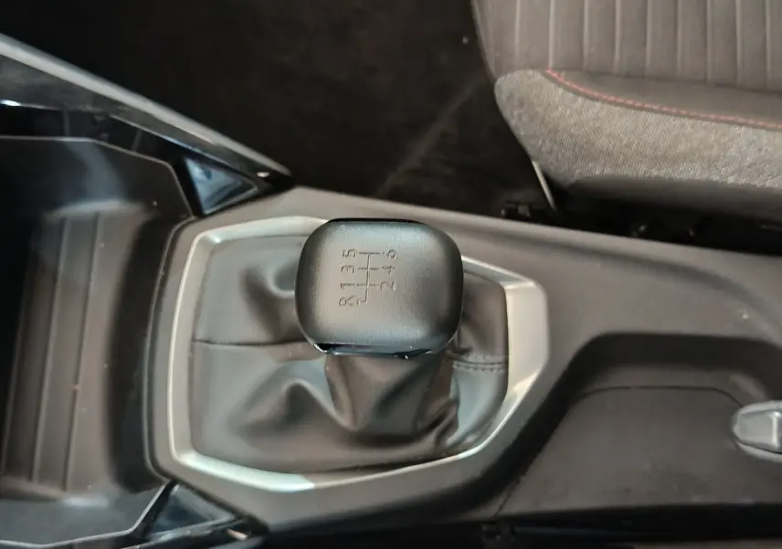 Le levier de vitesses manuel noir de la Peugeot 208 PureTech 100 vue de dessus, avec console centrale grise.