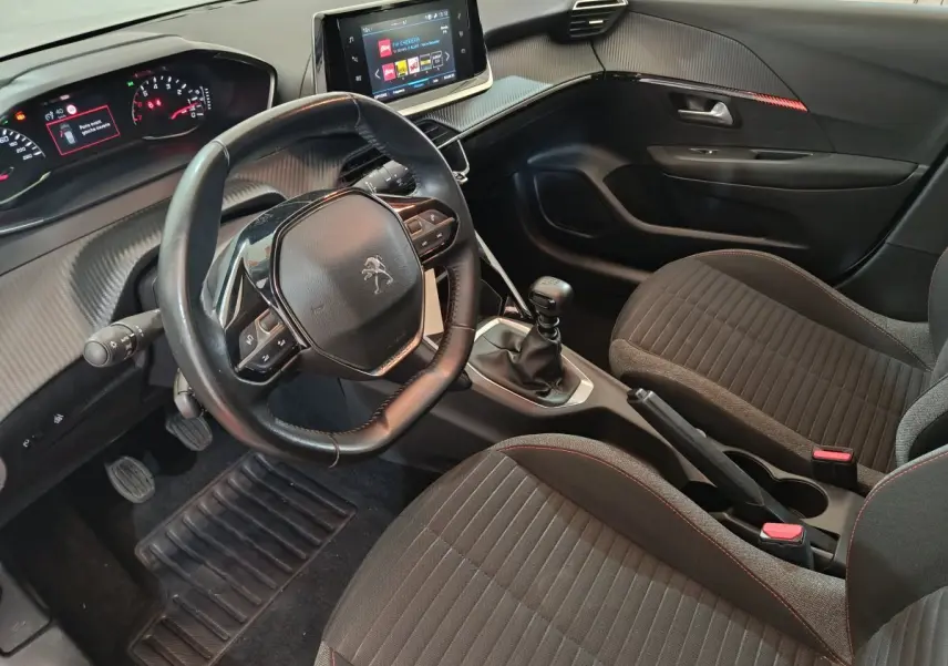 Vue intérieure côté conducteur du Peugeot 208 blanc 2020, volant cuir, tableau de bord numérique et écran tactile central.