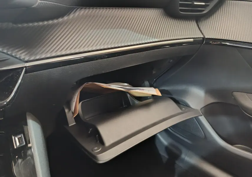 Gros plan sur la boîte à gants ouverte côté passager du Peugeot 208 2020 avec tableau de bord noir texturé.