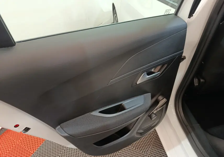 Vue intérieure de la porte arrière gauche noire d'une Peugeot 208 blanche, avec poignée et manivelle de vitre.