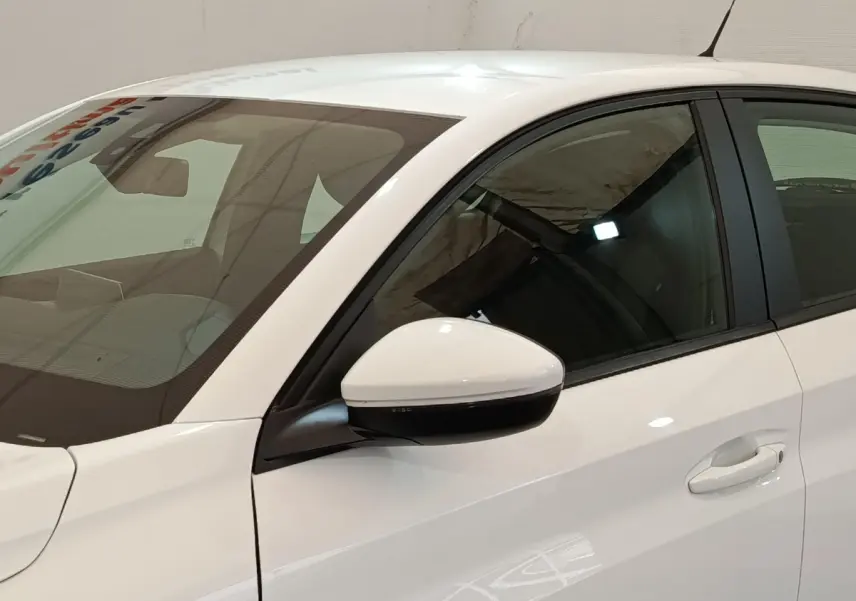 Vue rapprochée du côté gauche avant d'une Peugeot 208 blanche, mettant en valeur la portière et le rétroviseur.