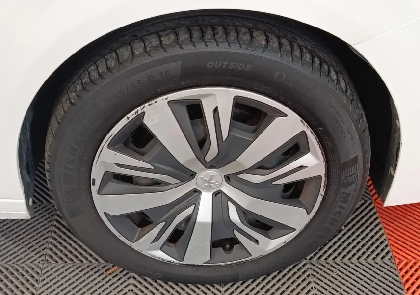 Gros plan sur la roue avant gauche blanche d'une Peugeot 208 PureTech 100 S&S Active Business avec jante stylisée.