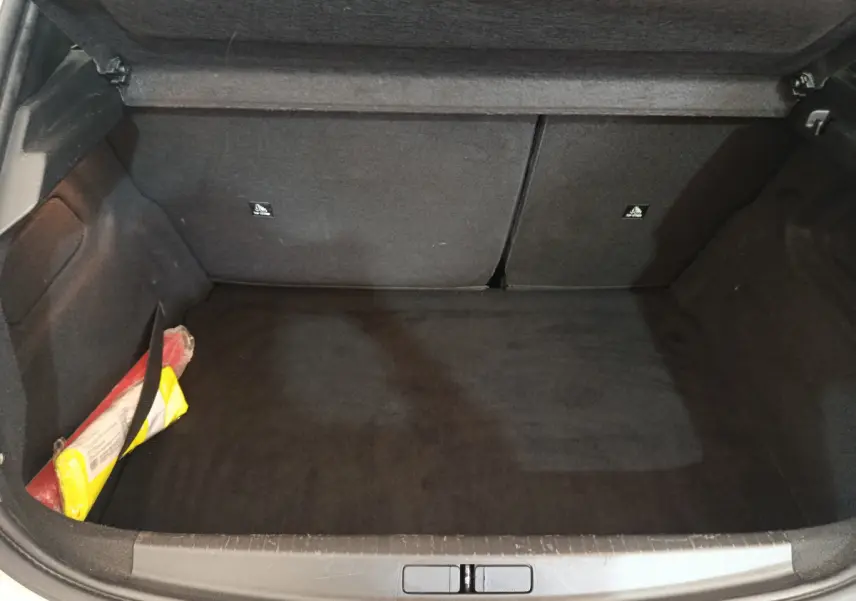 Coffre ouvert noir de la Peugeot 208 blanche 2020, avec kit de sécurité visible sur le côté gauche.