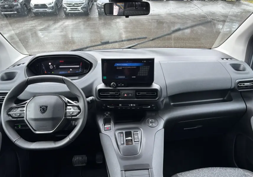 Vue intérieure du tableau de bord et volant cuir multifonctions du Peugeot Rifter gris Artense 2025, avec écran tactile central.