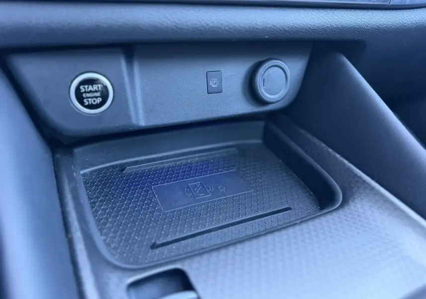 Gros plan sur le chargeur à induction et bouton Start/Stop dans l’habitacle noir du Nissan Qashqai 2025.