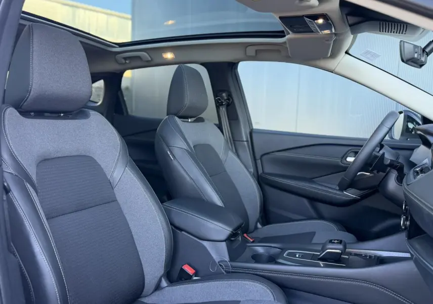 Vue intérieure côté droit du Nissan Qashqai 2025, sièges bi-matière gris, toit panoramique en verre ouvert.
