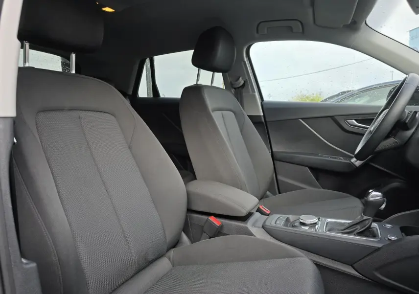 Vue intérieure côté droit de l'Audi Q2 2023 avec sièges tissu gris et console centrale équipée d'une boîte automatique.