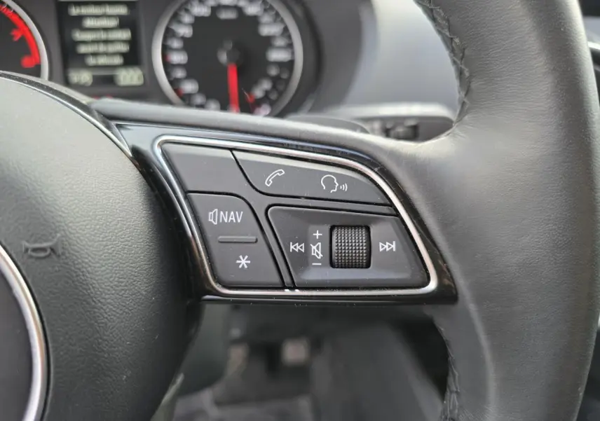 Gros plan sur les commandes du volant cuir noir de l'Audi Q2 35 TFSI 150 Design S-Line 2023.