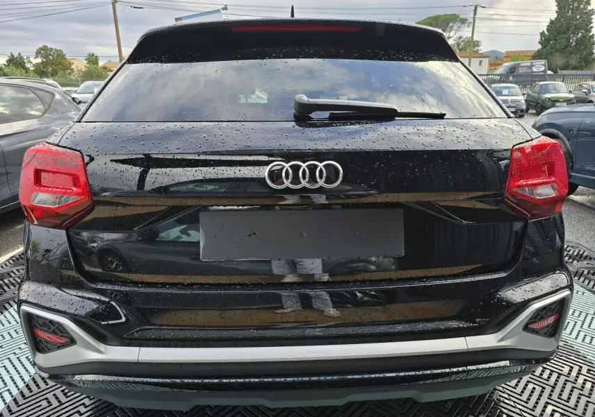 Vue arrière d'un Audi Q2 noir mythic 2023 avec feux rouges et lunette arrière surteintée.