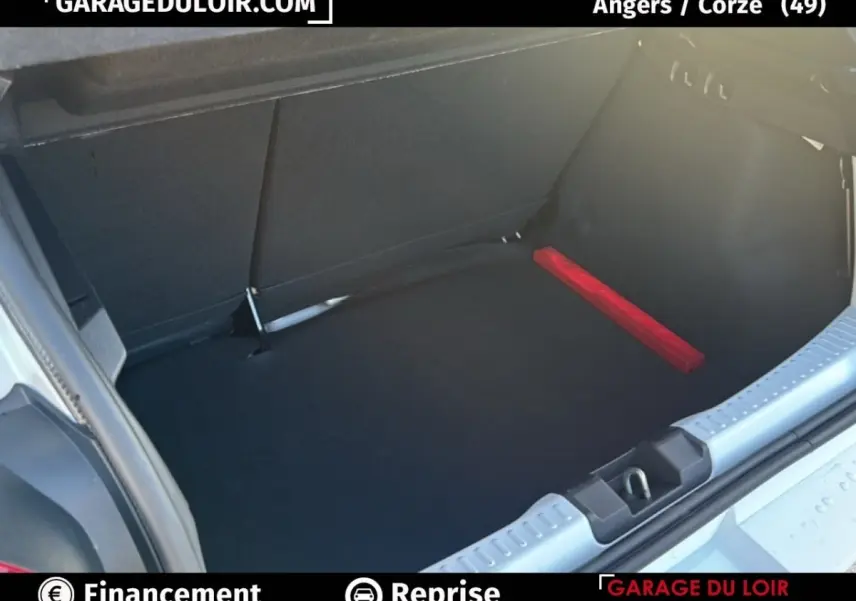 Coffre ouvert d’une Dacia Sandero blanche 2025, vue arrière montrant un espace de chargement propre avec triangle de signalisation rouge.