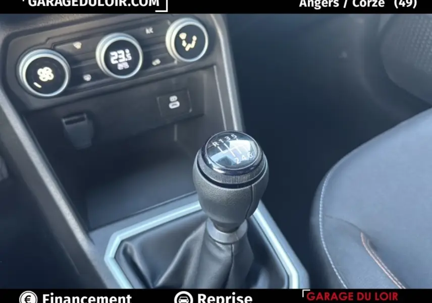 Gros plan sur le levier de vitesses manuel noir de la Dacia Sandero Expression TCe 90 2025 avec console et commandes clim visibles.