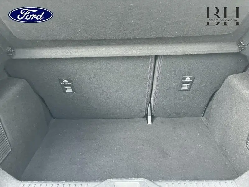 Coffre vide en vue plongeante de la Ford Fiesta 1.0 Flexifuel blanc Glacier, montrant la banquette arrière rabattable et les fixations Isofix.
