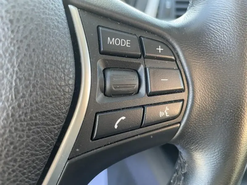 Gros plan sur les commandes au volant côté gauche d'une BMW Série 4 Gran Coupé noir métal de 2018.