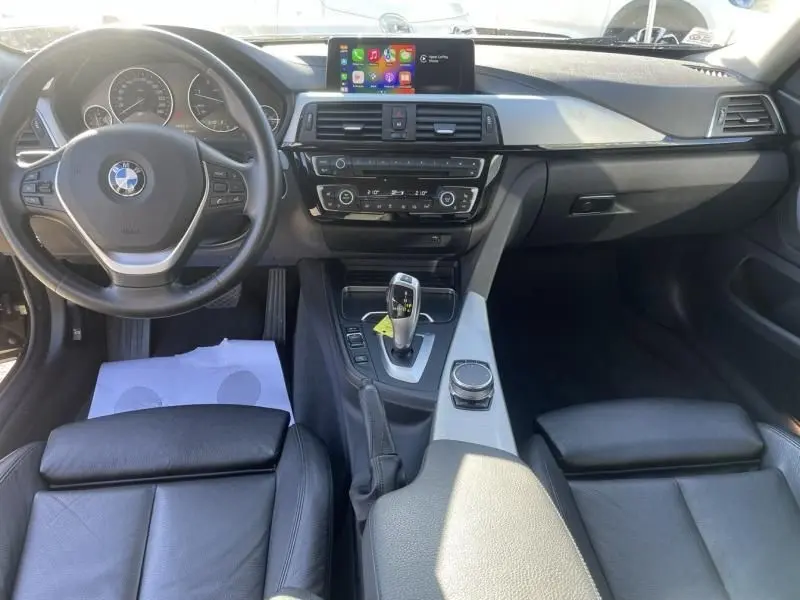 Vue intérieure de face du tableau de bord et console centrale d'une BMW Série 4 Gran Coupé 418 da 2018 avec sellerie cuir noire et écran tactile.
