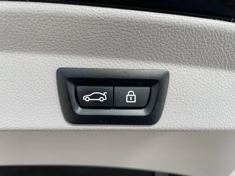 Gros plan sur les boutons d’ouverture du coffre et de verrouillage, sur fond de cuir beige clair intérieur BMW Série 4 Gran Coupé.