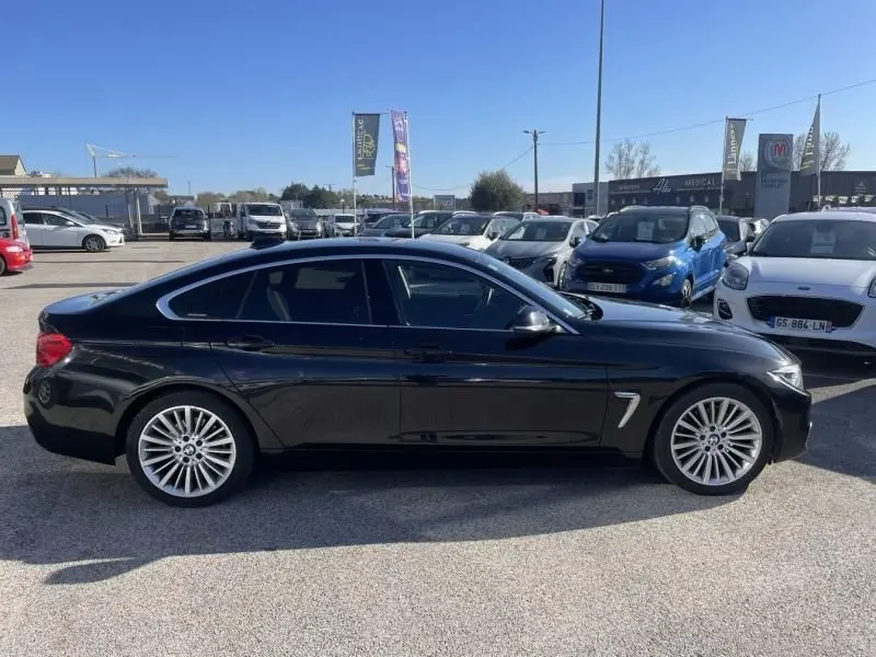 BMW Série 4 Gran Coupé noir métal vue de profil côté gauche, soulignant ses jantes alliage et lignes élégantes.