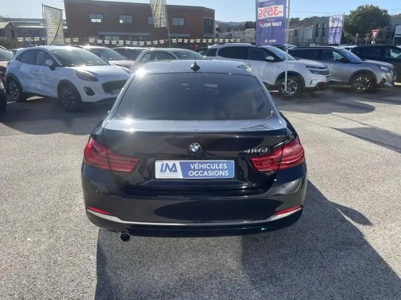 Vue arrière d'une BMW Série 4 Gran Coupé 418 da noire métal de 2018 avec feux rouges et plaque d'occasion visible.