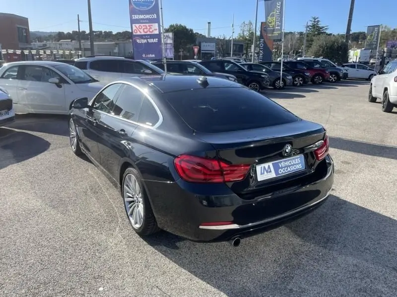 BMW Série 4 Gran Coupé 418 da noir métal vue 3/4 arrière droit, avec feux arrière rouges et jantes alliage.