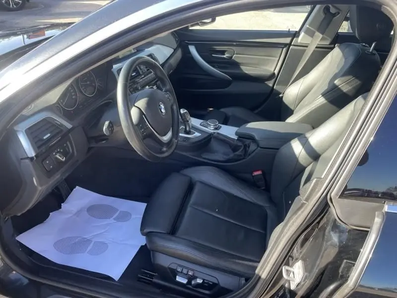 Vue intérieure côté conducteur de la BMW Série 4 Gran Coupé 418 da 2018 noir métal avec sellerie cuir et console centrale visible.
