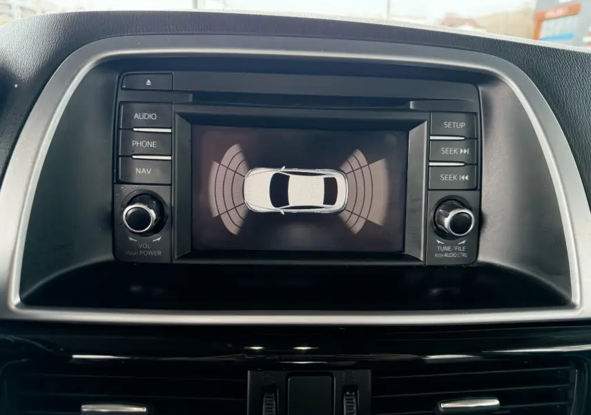 Écran central du Mazda CX-5 2013 montrant l'affichage du système d'aide au stationnement avec boutons de commande autour.