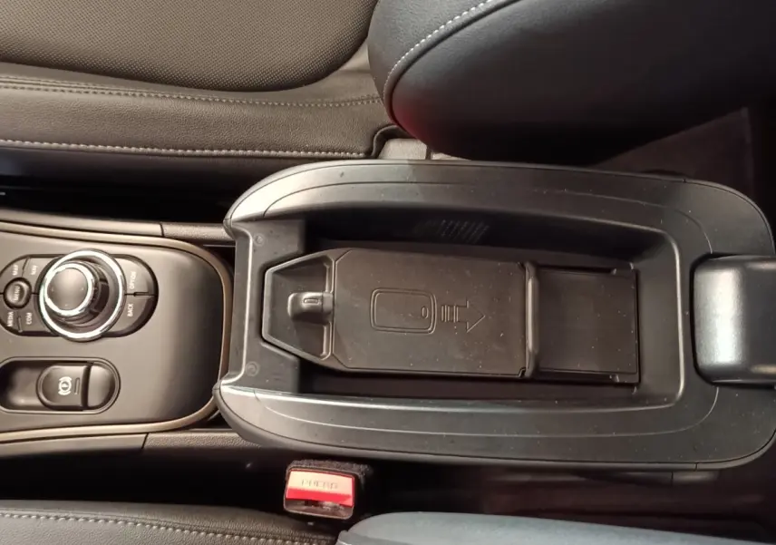 Vue plongeante sur la console centrale noire du MINI Countryman Cooper SE avec rangement réfrigéré et commandes circulaires.