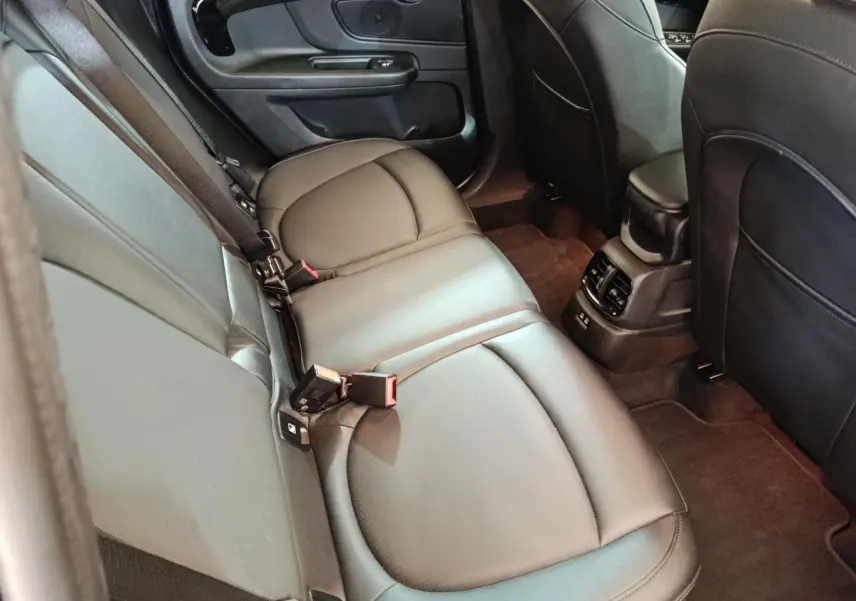 Vue intérieure arrière côté gauche du MINI Countryman Cooper SE Essential 2023, sièges cuir noirs et console centrale avec aérateurs.