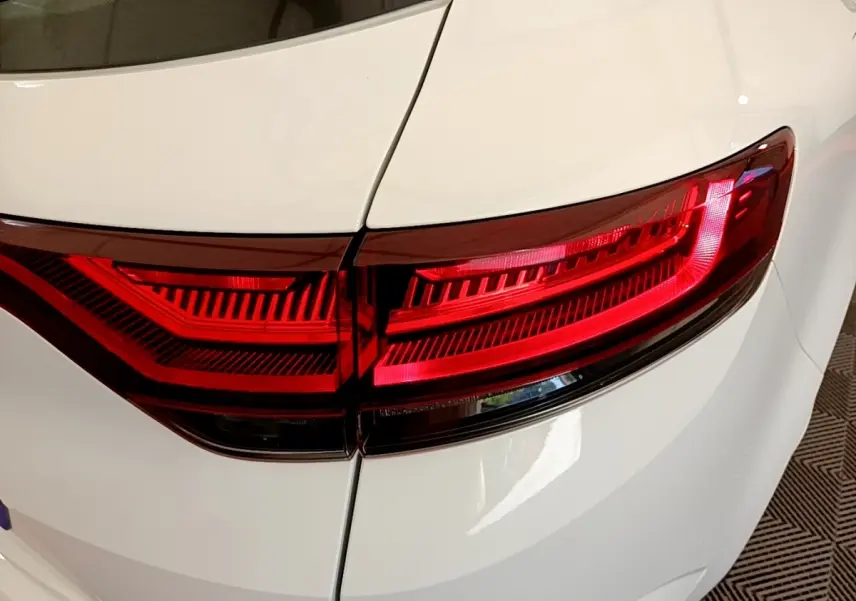 Gros plan sur le feu arrière droit rouge d’une Renault Mégane Business E-Tech hybride rechargeable blanche, vue arrière.