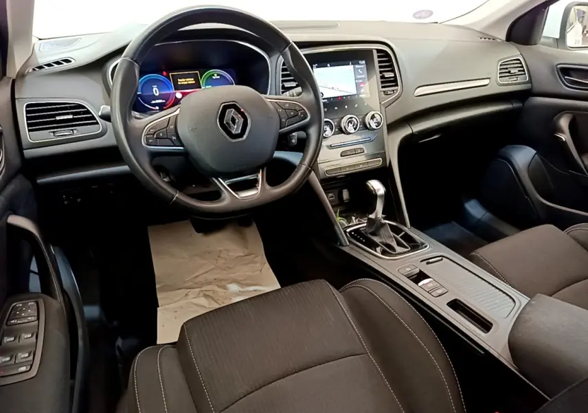 Vue intérieure avant de la Renault Mégane Business E-Tech hybride, tableau de bord noir avec écran tactile et volant multifonctions.