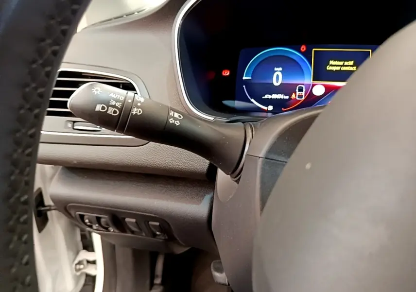 Vue rapprochée du combiné d'instruments digital et commande des phares à gauche sur Renault Mégane Business E-Tech hybride blanc.
