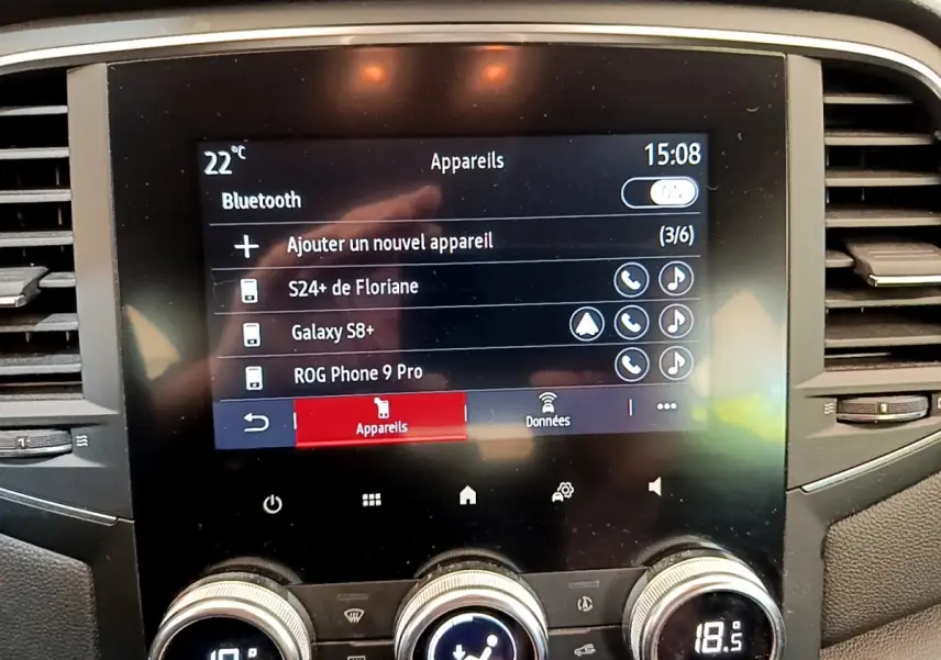 Écran tactile central de la Renault Mégane Business E-Tech hybride blanc, affichage Bluetooth et commandes climatisation visibles.