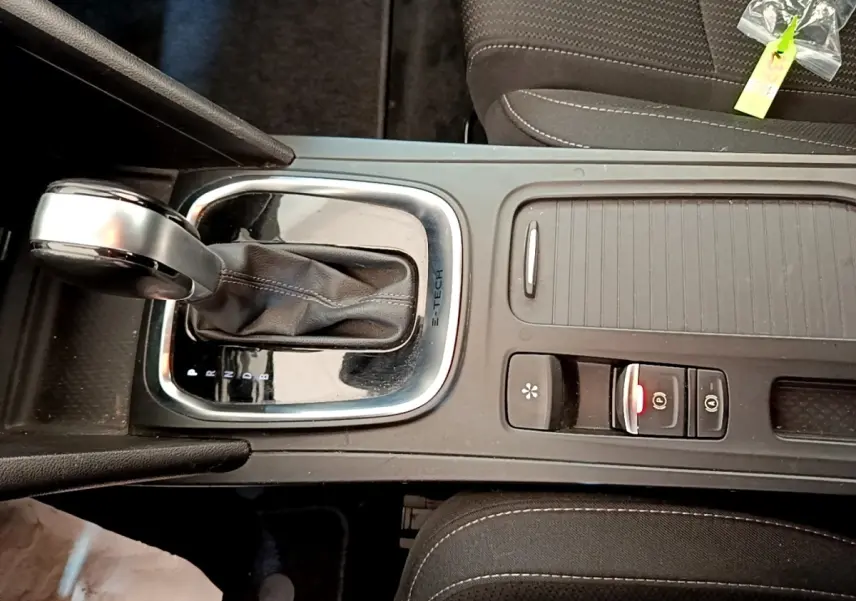 Gros plan sur la console centrale noire de la Renault Mégane Business E-Tech hybride, avec levier de vitesse automatique et commandes.