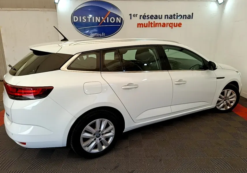 Renault Mégane Business E-Tech hybride blanche vue de profil droit en stationnement intérieur, jantes alliage visibles.