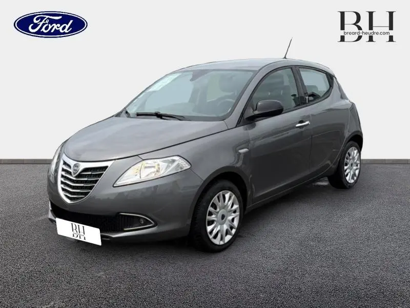 Lancia Ypsilon gris Argento vue 3/4 avant droit, avec calandre chromée et phares halogènes visibles.