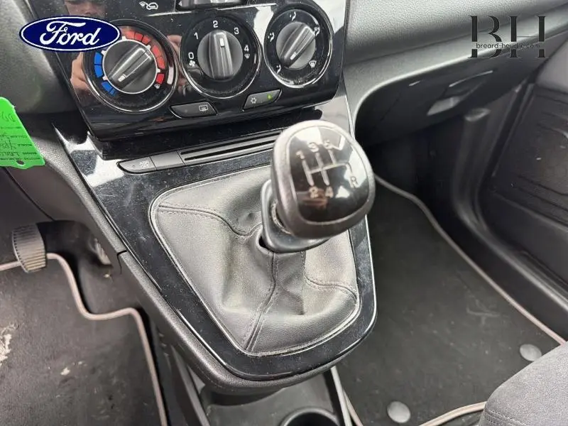 Gros plan sur la commande de boîte manuelle en cuir noir et la console centrale d’une Lancia Ypsilon gris Argento.