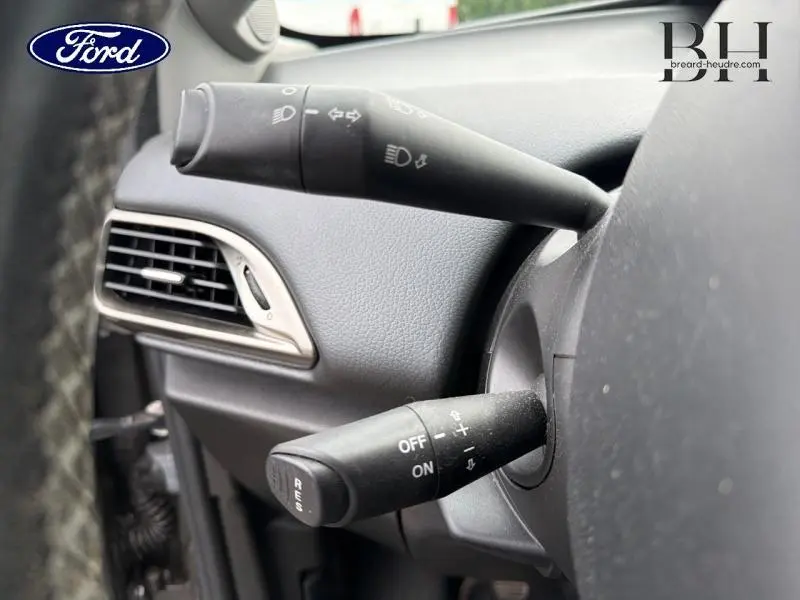 Détail intérieur montrant les commandes de clignotants et régulateur de vitesse sur un volant noir d'une Lancia Ypsilon 2014.