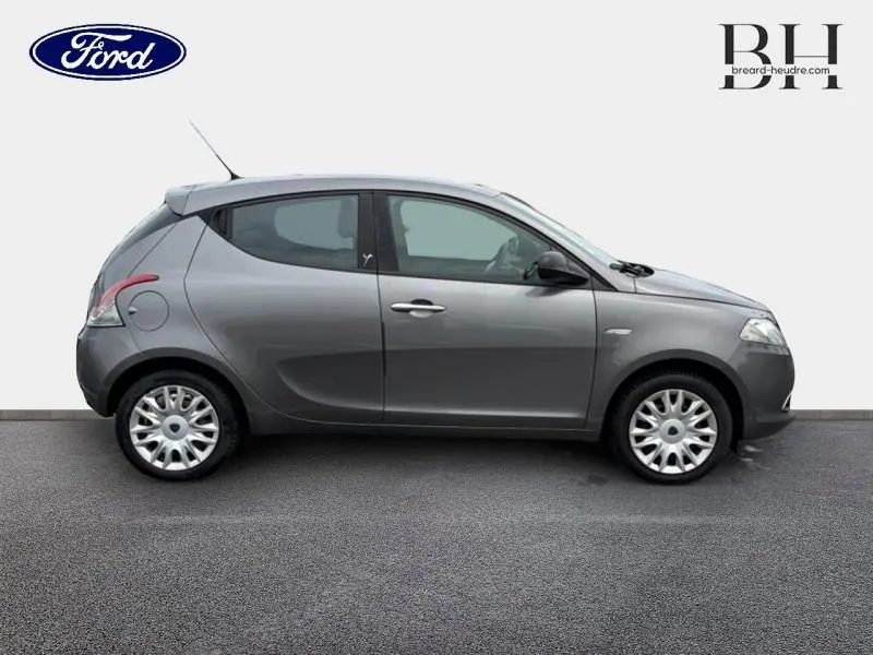Vue de profil côté gauche d'une Lancia Ypsilon 1.2 8v Gold gris Argento avec jantes argentées et vitres teintées.