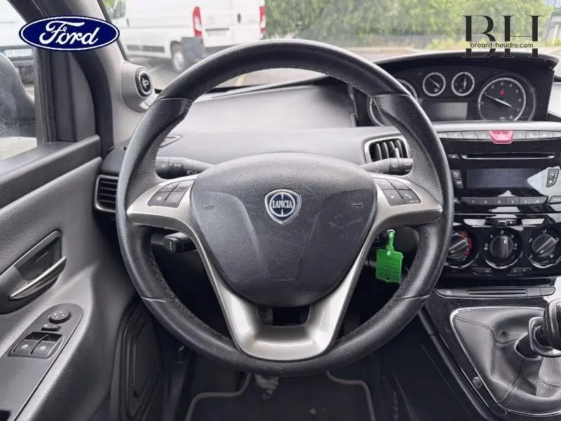 Vue intérieure centrée sur le volant cuir noir de la Lancia Ypsilon 2014 avec tableau de bord et commandes manuelles visibles.