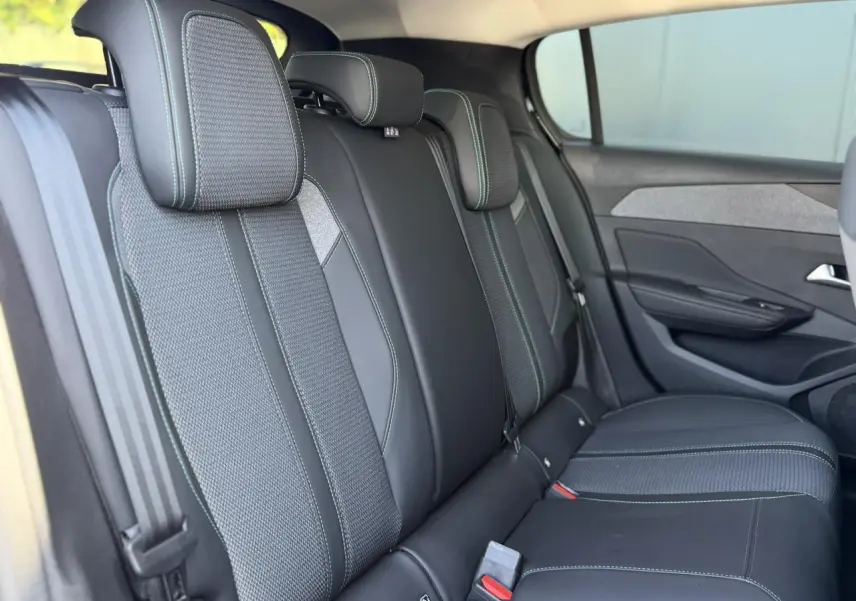 Vue latérale des sièges arrière noirs avec surpiqûres bleues de la Peugeot 308 Hybrid 2025, finition Allure.