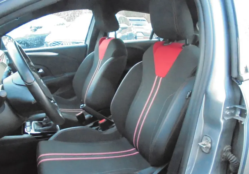 Vue intérieure côté conducteur de l’Opel Corsa gris quartz, sièges noirs avec inserts rouges et coutures contrastées.