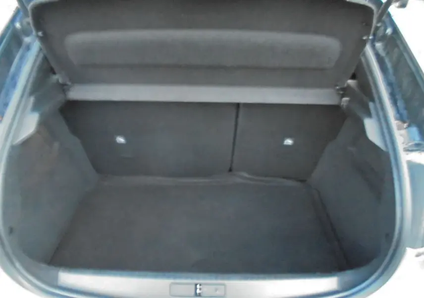 Coffre ouvert de l’Opel Corsa gris quartz metal, vue plongeante sur l’espace de chargement vide.