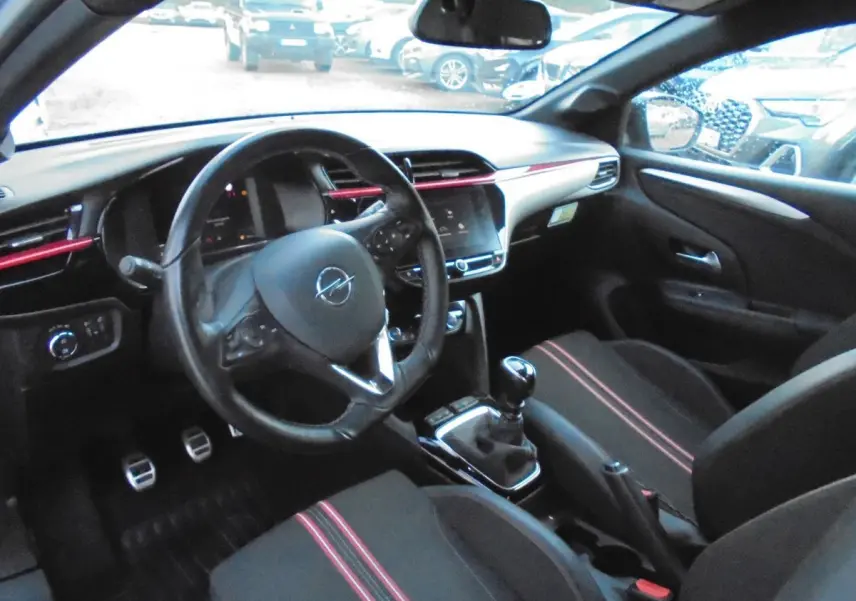Intérieur de l'Opel Corsa 1.2T 100 CH GS-Line 2021, vue côté conducteur, sièges noirs avec surpiqûres rouges.
