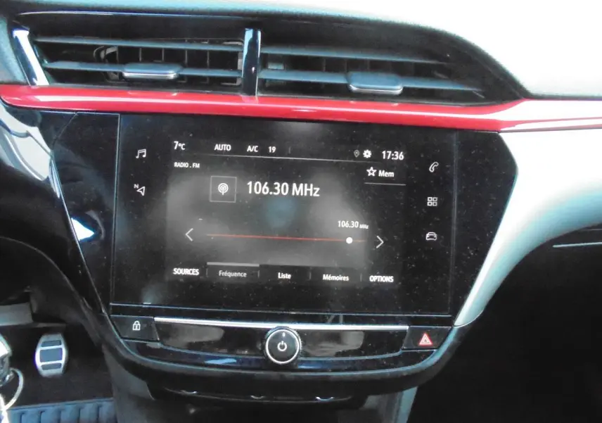Tableau de bord de l’Opel Corsa gris quartz, avec écran tactile radio affichant 106.30 MHz et bandeau rouge décoratif.